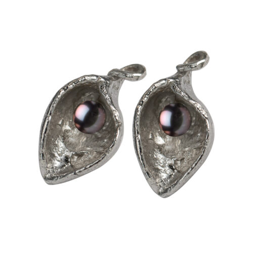 Handcrafted sterling silver earrings with organic sculptural shape cradling a freshwater pearl, available in white or black.