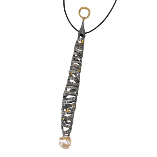 Long pendant necklace featuring a vertically elongated sculptural form wrapped in intersecting darkened metal bands, accented with small gold drops throughout, suspended from a black cord with a textured gold ring at the top and finished with an organic pearl at the base.
