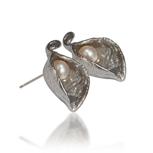 Handcrafted sterling silver earrings with organic sculptural shape cradling a freshwater pearl, available in white or black.